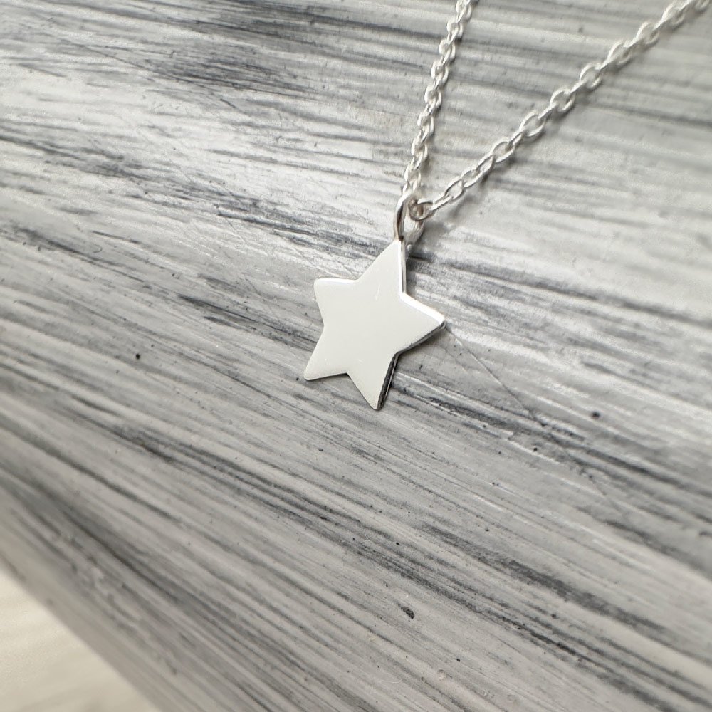 A17-Shine-Bright-Anklet-Sterling-Silver-(2) Solid silver dainty five pointed star charm on an anklet on a grey and white background.