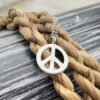 Close up of a peace sign anklet charm presented on a twisted rope.