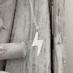 Anklet in 925 sterling silver with a shiny silver lightning bolt pendant hanging from a wood background.