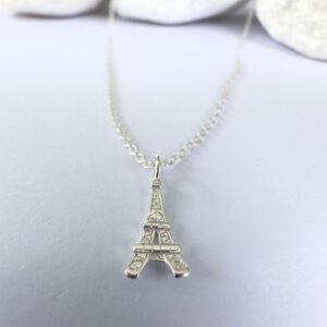 Close up of an elegant Parisien chic anklet in silver with a pendant of the Eiffel Tower.