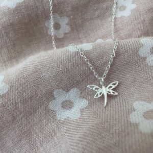 Beautiful dragonfly charm on a sterling silver ankle bracelet on a pink and white daisy fabric.