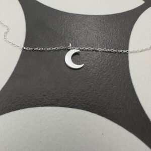 Sterling silver anklet with silver crescent moon charm on a black and white background.