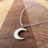 Crescent moon on a silver ankle bracelet on a wooden background.