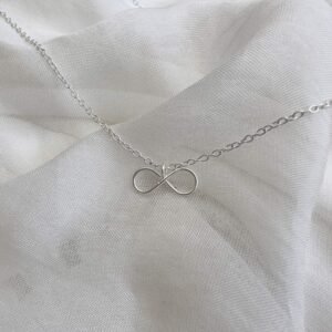Dainty infinity charm on a silver ankle bracelet.
