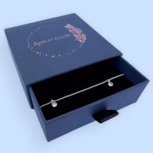 Sterling silver anklet with three pink gemstones, presented in a blue jewellery box with Anklet Allure written on the top in rose gold.