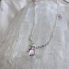 Passionate pink coloured gemstones positioned around a sterling silver ankle bracelet, on top of a white crystal.