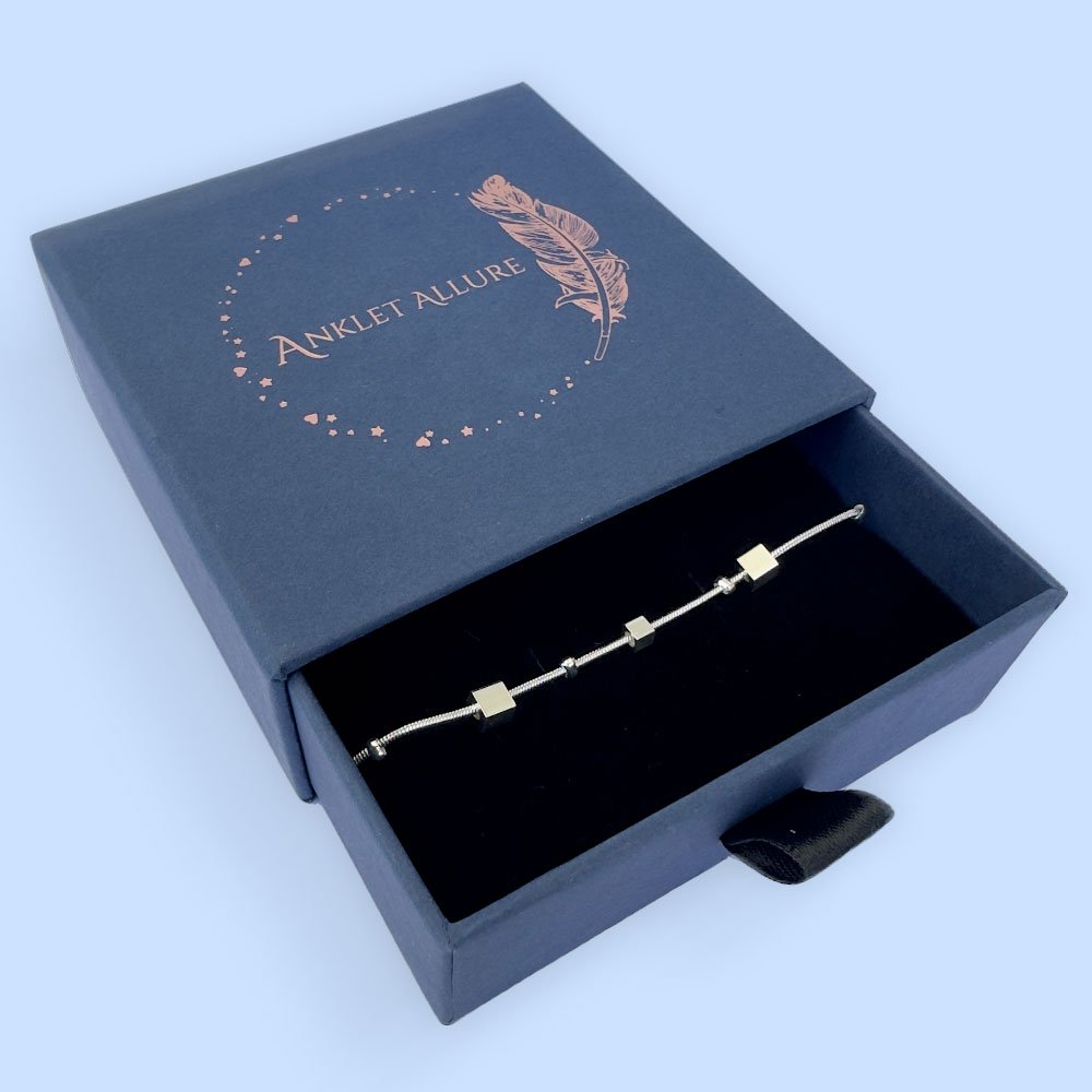 B2-Anklet-box Ankle bracelet in silver with different sized square charms in a blue jewellery box.