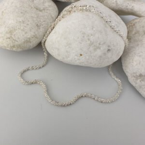 A simple sparkly ankle bracelet on a white rock.