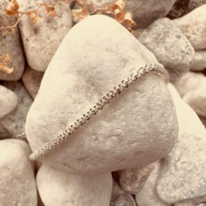 Simple sparkley silver anklet on a white rock.