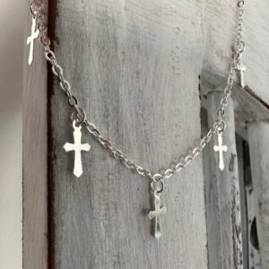 Gothic style silver anklet with five crosses around the chain, hanging off white washed wood.