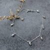 Sterling silver anklet with seven small tulip flower shaped charms in equal distance around the ankle chain.