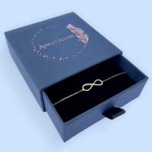 Dainty gold double chain anklet with a sold gold heart charm presented in a dark blue Anklet Allure gift box.