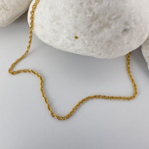 Simple gold anklet presented on a white rock.