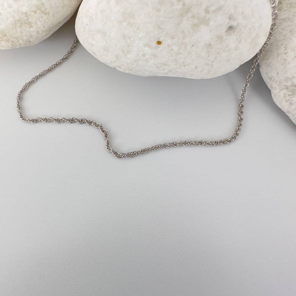 C6-Anklet-(2) Plain silver anklet draped on three white rocks.