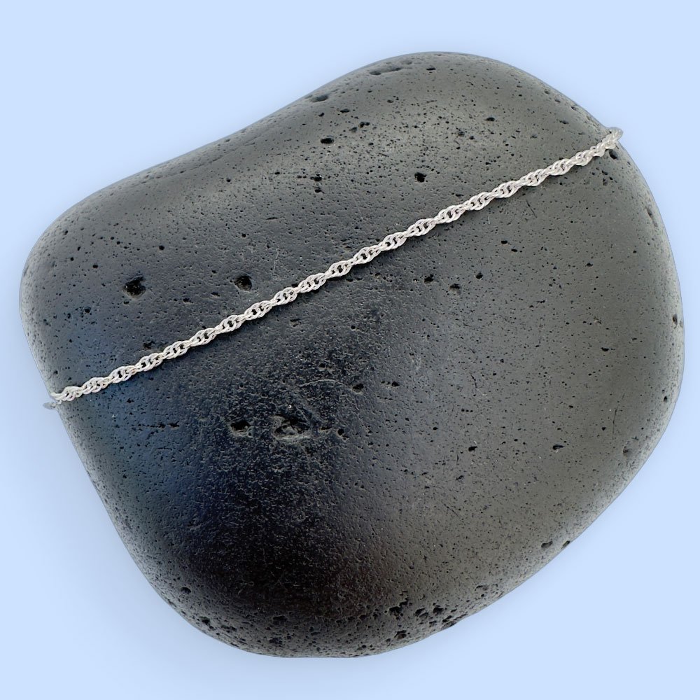 C6-Anklet-rock Plain silver chain displayed on a black rock.