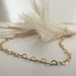 Stunning gold anklet made of interlinking identical hearts draped over a white feather.