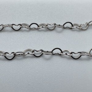 Close up of identical silver hearts interlinked to make a dainty anklet.