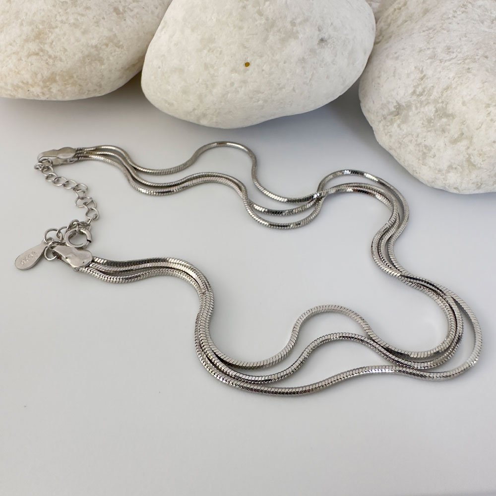 D1-Anklet-(4) Triple chain silver anklet with white rocks behind.