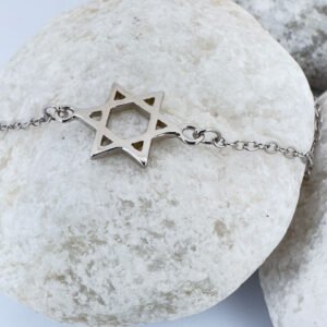 Silver anklet with a star of David charm on a white rock.