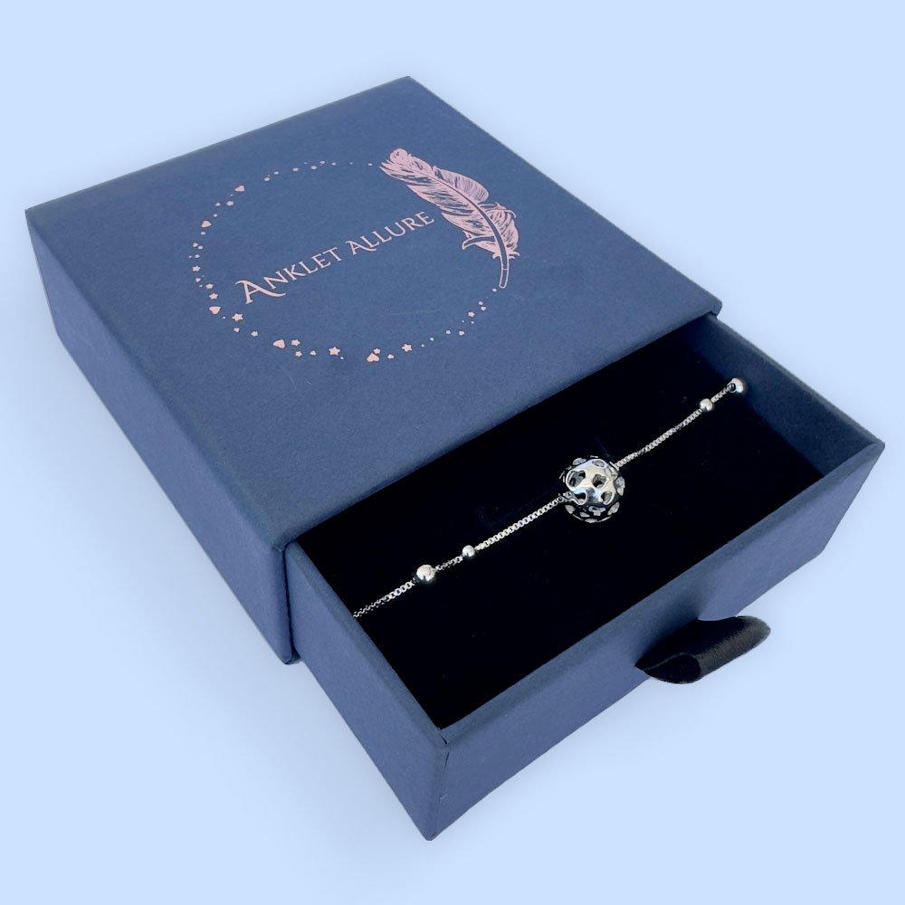 D8-Anklet-box Silver anklet with a large silver sphere charm in a blue jewellery box.
