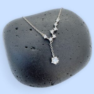 Celestial anklet with seven white gemstones and a large gemstone hanging down, on a black rock.