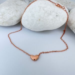 Stunning rose gold anklet with a cute solid rose gold heart charm on white rocks.