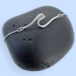 Sterling silver anklet with a surf wave design on a black rock.