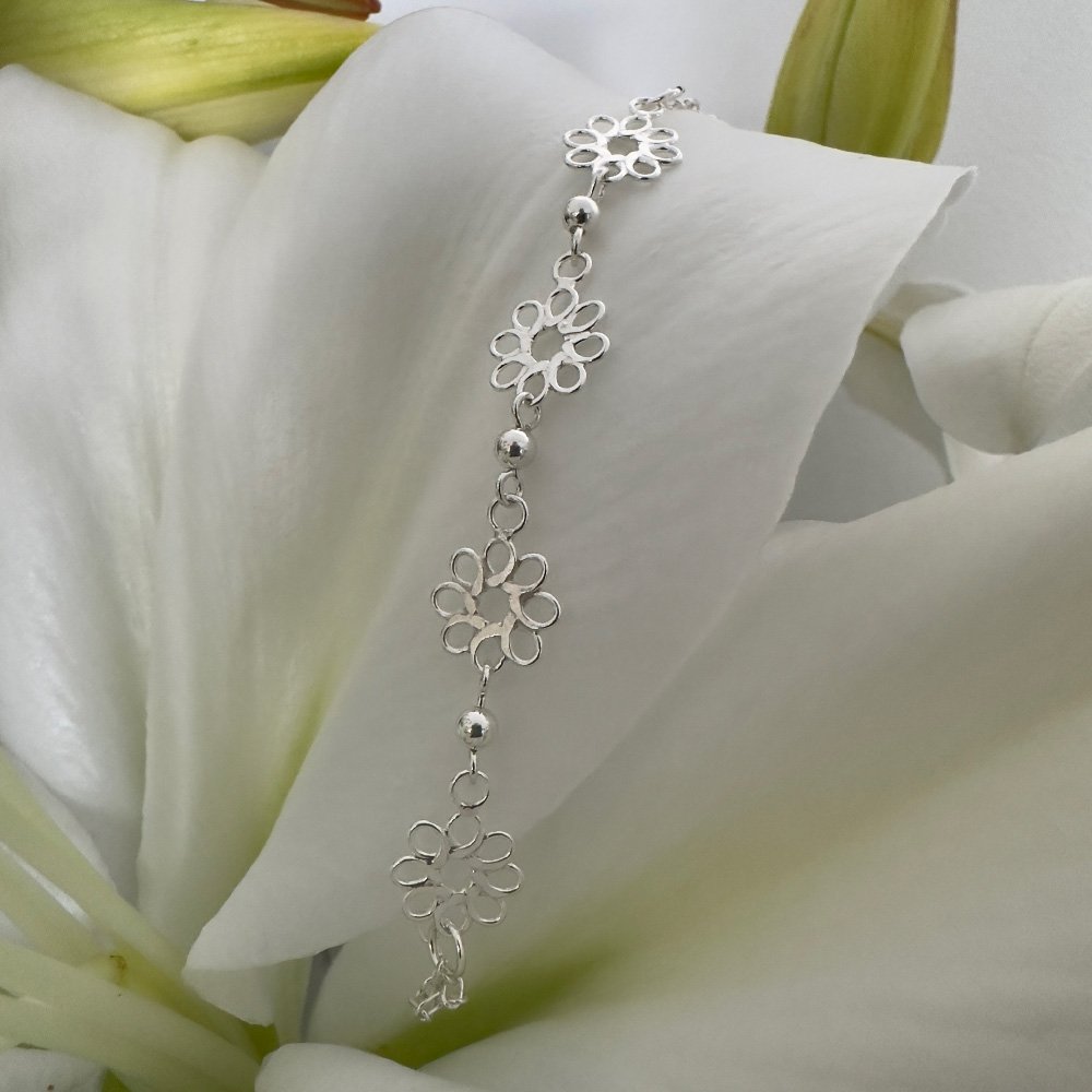 G13-You-Are-Deserving-Anklet-main-image Sterling silver anklet featuring four identical flowers with eight petals each, linked together and draped on a white lily petal for display purposes.