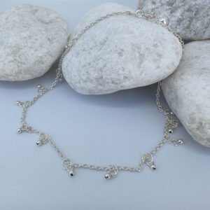 Dainty and gracious ankle bracelet with two hoops and a ball charms all the way around on white rocks.