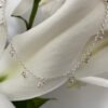 A gracious looking anklet with lots of small sterling silver balls hanging from it, equally spaced all the way around a dainty ankle chain, presented on a white lily petal.